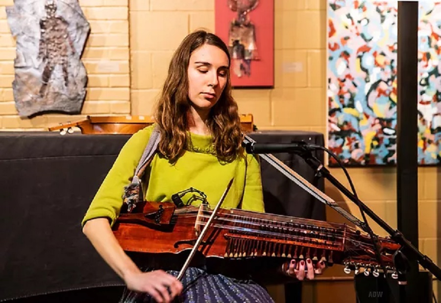 Alyssa Rodriguez wearing a lime green shirt and a stringed instrument on her lap.