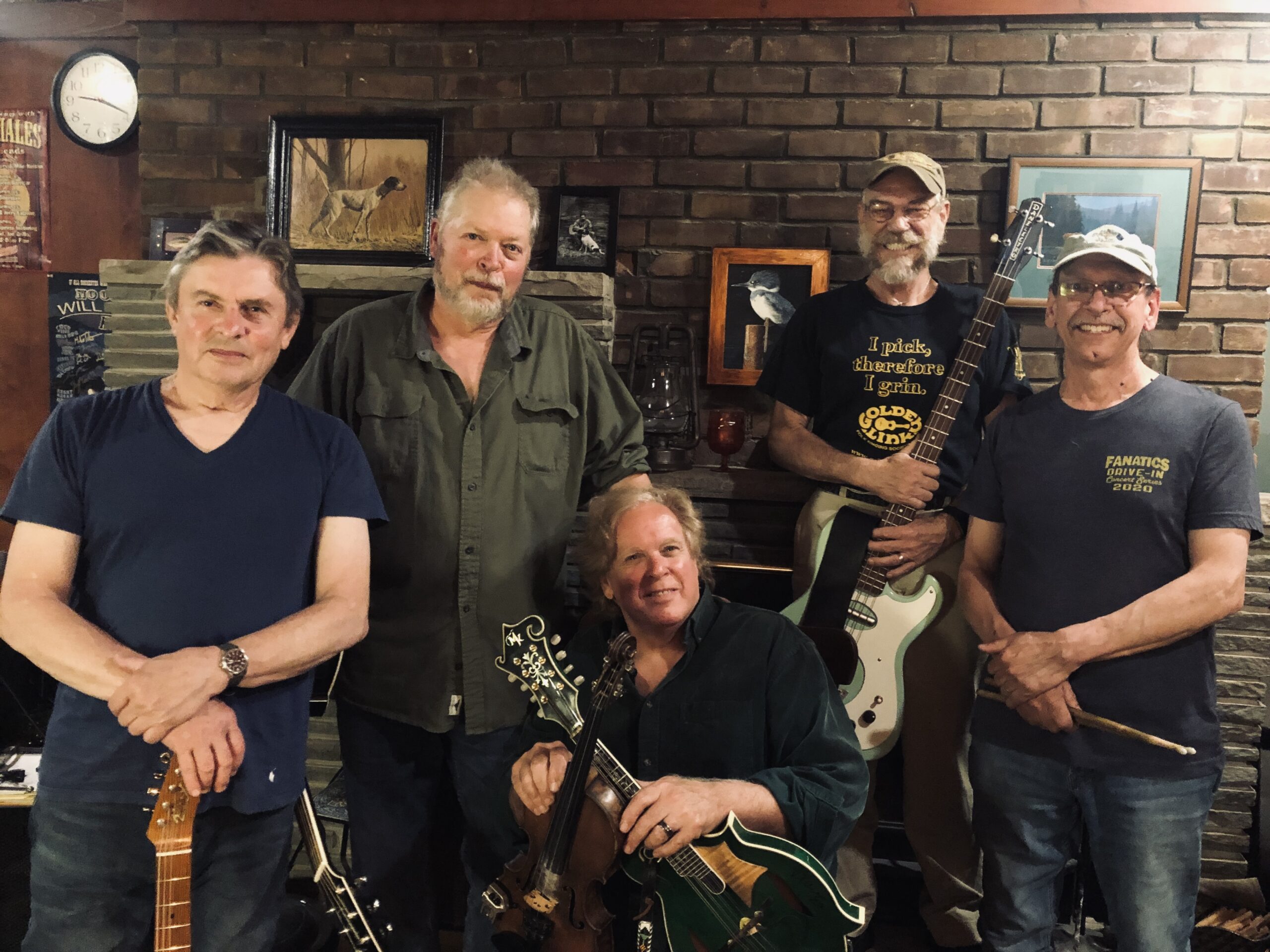 Jeff Riales and the Silvertone Express band holding their guitars, drum sticks, etc., while standing in front of a brick wall.