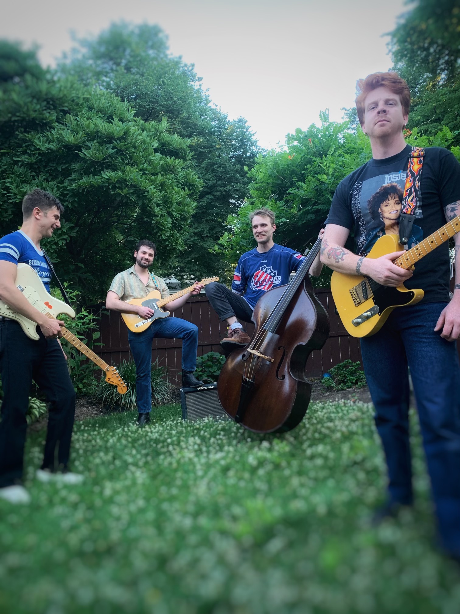 Texas Headphones posing in a lush yard with their electric and string instruments.